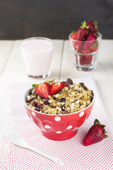 Granola with strawberry and yogurt on a white wooden background
