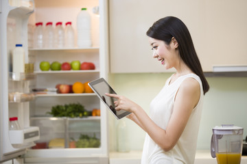 Young woman using digital tablet in kitchen