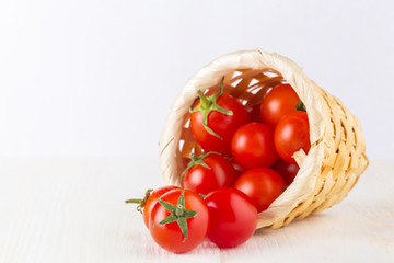 Tomatoes in basket on white wooden background