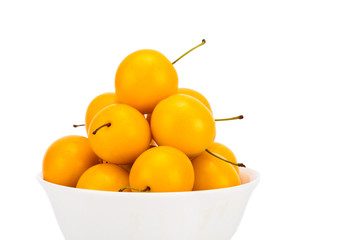 Handful of yellow cherry plums in ceramic bowl - isolated on white background