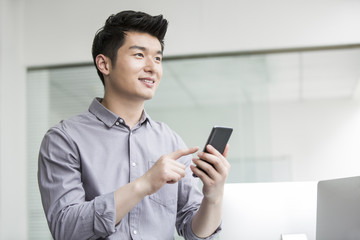 Young businessman using smart phone in office