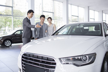 Young couple choosing car in showroom