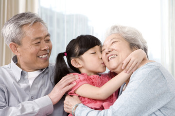 Obraz premium Elderly couple with granddaughter on couch