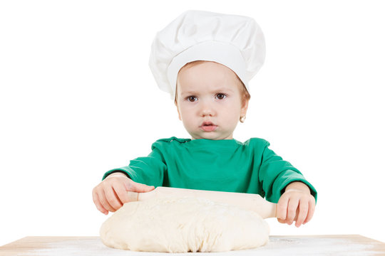 Serious little boy kneading dough for the cookies, isolated on white