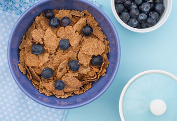 A healthy breakfast of bran flakes and blueberries. Looking down onto the table from above.