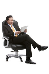 Senior businessman using digital tablet on director's chair