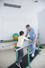 Male therapist with boy in parallel bars