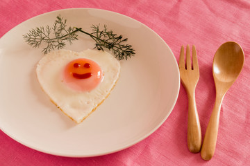 Fried egg in shape of heart on plate top view