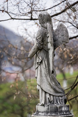 Old tombstone sculpture of an angel with broken arm and wings on the cemetery.