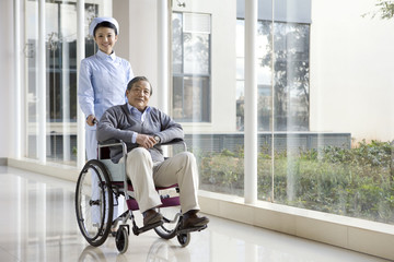 Nurse Pushes Senior Man in a Wheelchair