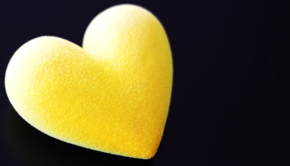 Soft blurred yellow fluffy heart on a black background, selective focus