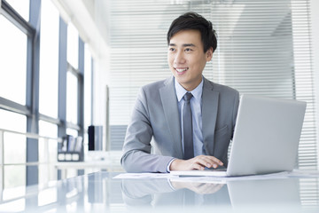 Young businessman using laptop in office