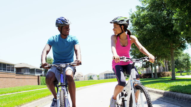 Young active African American couple cycling to keep fit outdoors