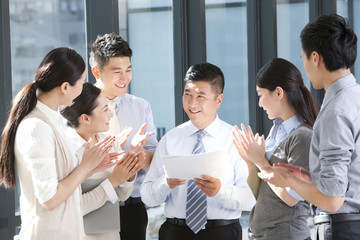 Businesspeople clapping and congratulating team leader