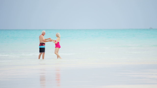 Senior Caucasian couple in swimwear dancing together on an island beach
