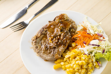 Beef Steak on white dish, plank wood background.