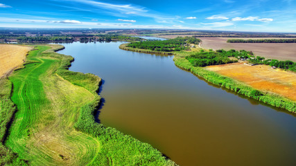 Rural, rustic landscape with river and wheat fields in summer da