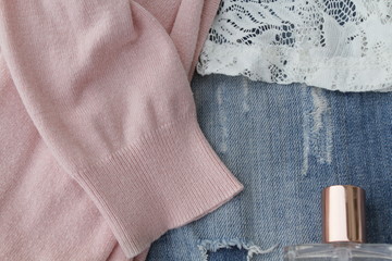 Worn ripped jeans, a lacy top and a pink cardigan with a bottle of pink perfume