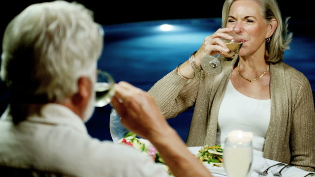 Retired Caucasian couple enjoying evening dinner at beach hotel