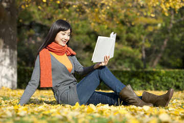 Young woman reading books in beautiful autumn day