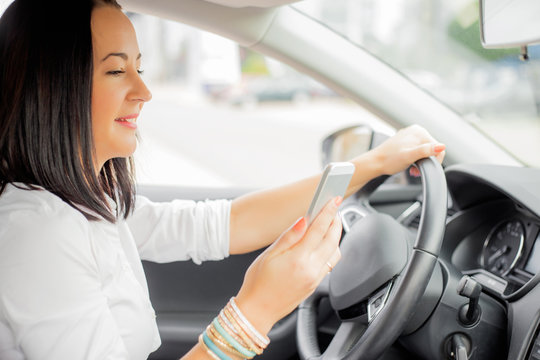 Distracted woman driver on her mobile device 