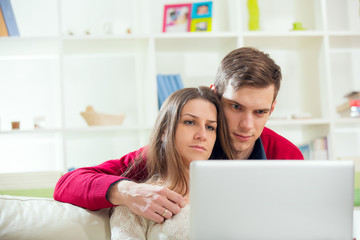 Young couple relaxing on sofa with laptop in the living room.Selective focus