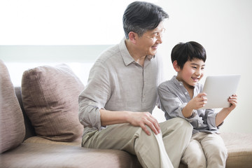 Happy grandfather and grandson with digital tablet