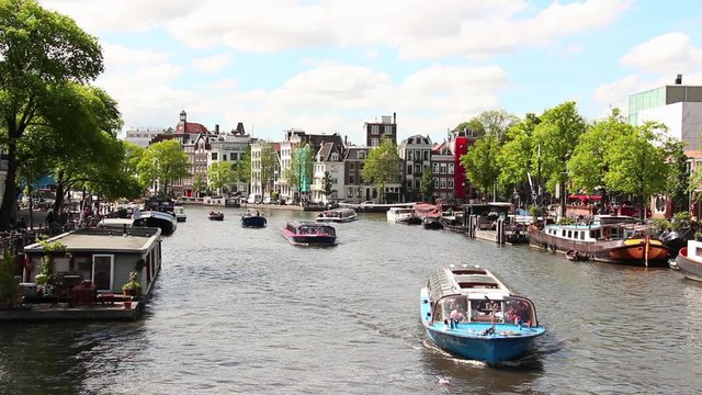 Time Lapse boats in a Canal of Amsterdam, Netherlands. Amsterdam is a large European capital with a number of historical buildings, monuments and museums. Its various canals itself add to its beauty.
