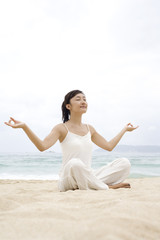 Fototapeta na wymiar A woman practicing yoga at the beach