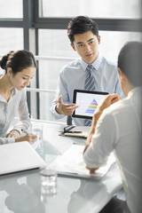 Young business people using digital tablet in office