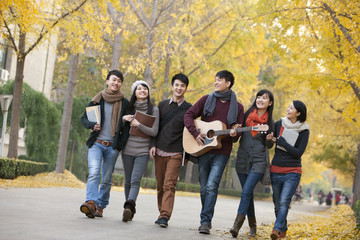 College students walking and playing guitar on campus in autumn
