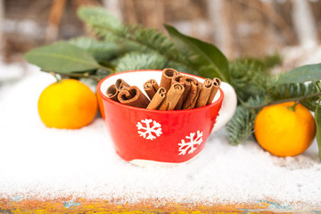 cinnamon sticks in a cup and tangerines