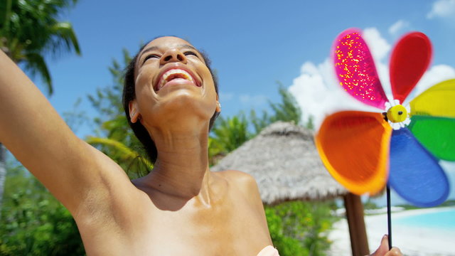 Young African American girl wearing bikini with toy pinwheel on beach