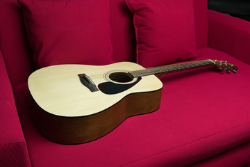 a guitar put on red sofa