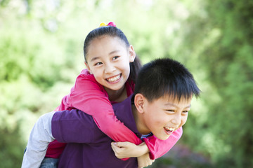 Young boy giving girl piggyback ride