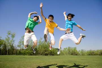 Fototapeta na wymiar Three young men jumping in the air at the park