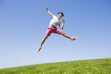 Cheerful young man jumping on grass
