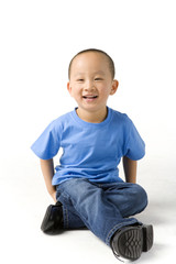 Young boy sits on the ground and smiles