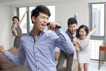 Obraz premium Happy young friends singing and dancing in living room