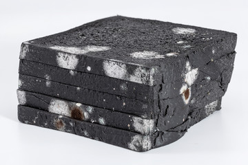 Moldy sliced black bread loaf over a white background.