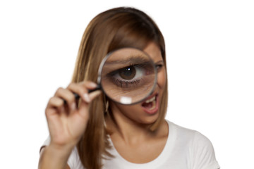 scowling young woman looking through a magnifying glass