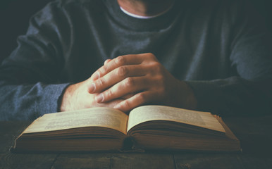 low key image of person sitting next to prayer book
