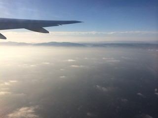 Fototapeta na wymiar Im Flugzeug über dem Pazifik vor Los Angeles, im Hintergrund ragen die San Bernadino Mountains durch die Wolkendecke