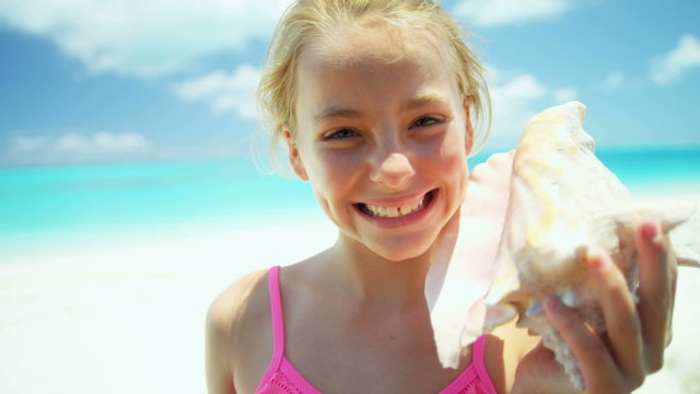 Portrait of a blonde Caucasian girl on a beach holding conch shell
