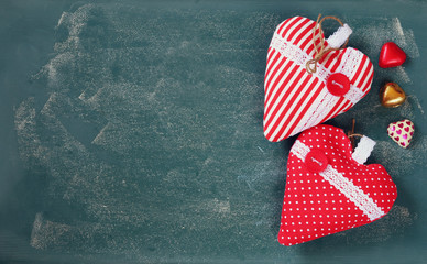 Obraz premium top view image of colorful heart shape chocolates, fabric hearts on blackboard background. valentine's day celebration concept 
