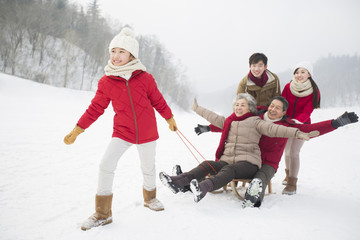 Fototapeta na wymiar Happy family playing with sled on the snow