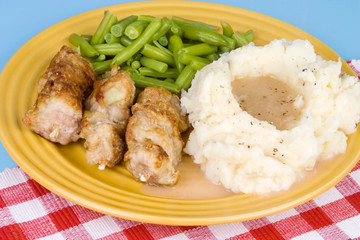 City Chicken with Mashed Potatoes – City chicken (cubes of pork on a skewer, a midwest favorite) with mashed potatoes, gravy, and green beans on a plate.