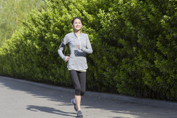 Happy mature woman running and listening to music in park