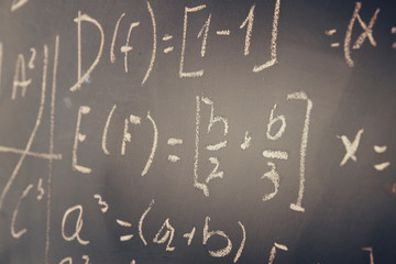 side view of math formulas and calculation written over chalkboard. selective focus.
