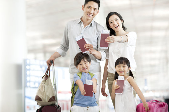Happy Young Family With Flight Tickets And Passports At The Airport